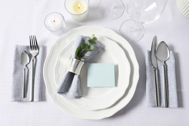 Beautiful table setting with blank card and floral decor, flat lay