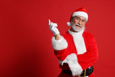 Photo of Merry Christmas. Santa Claus posing on red background, space for text
