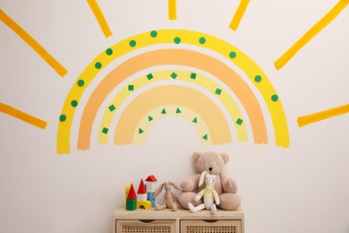 Photo of Cute child's room interior with beautiful sun painted on wall
