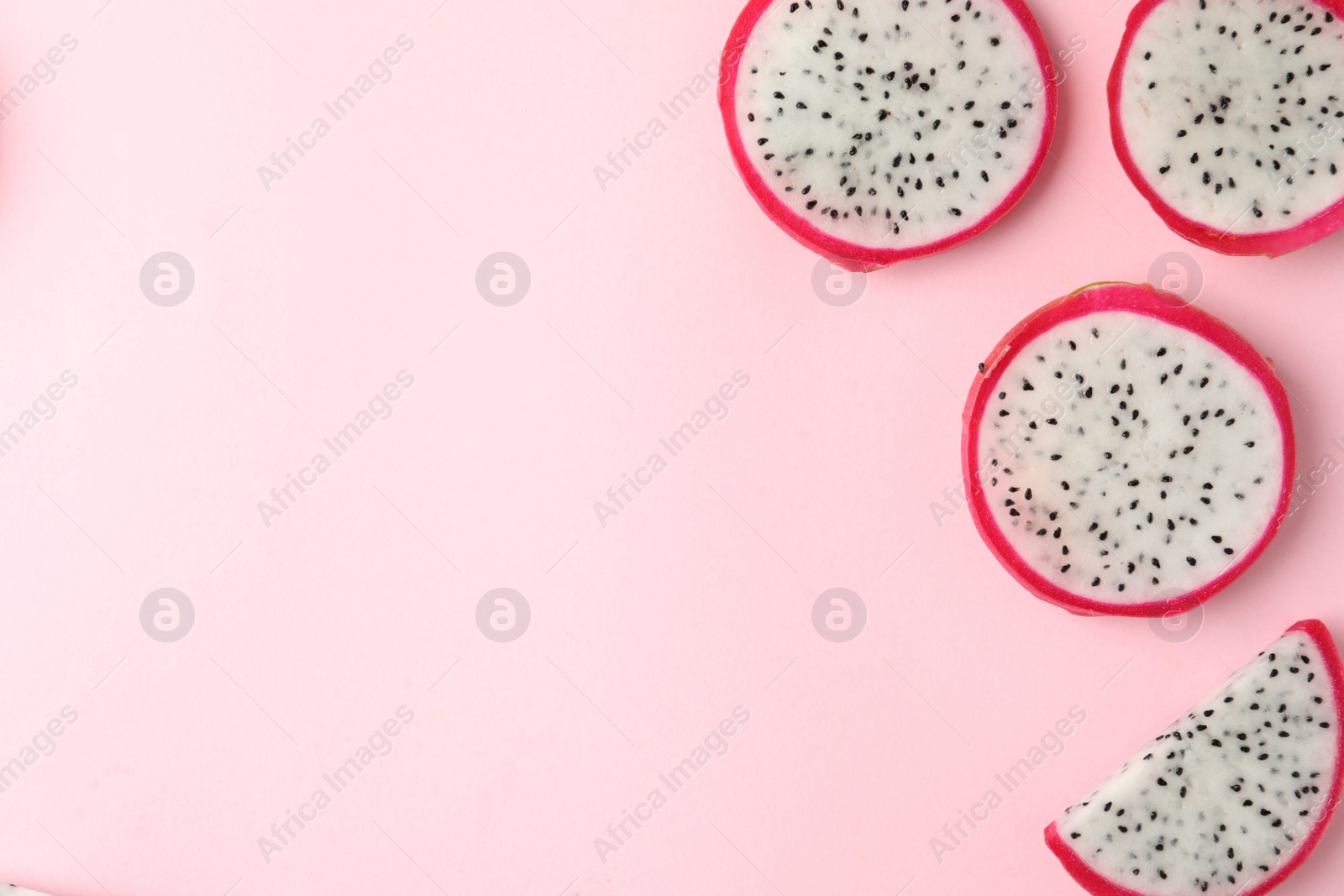 Photo of Slices of delicious dragon fruit (pitahaya) on pink background, flat lay. Space for text