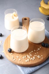 Photo of Tasty yogurt in glasses, oats and blueberries on grey table