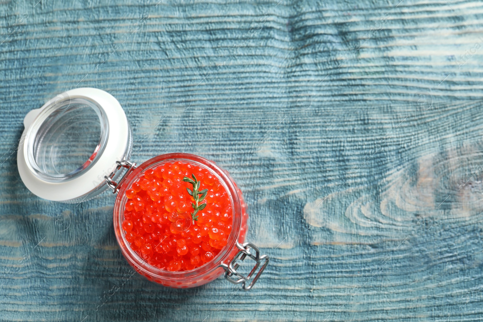 Photo of Glass jar with delicious red caviar on table