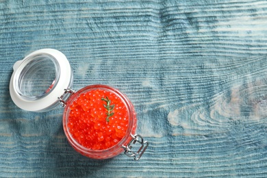 Glass jar with delicious red caviar on table