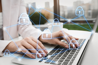 Image of Information security. Young woman using laptop at table indoors, closeup