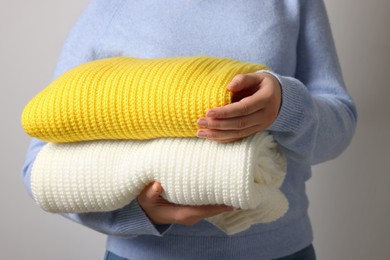 Photo of Woman with knitted sweaters on light background, closeup