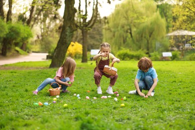 Photo of Easter celebration. Cute little children hunting eggs outdoors