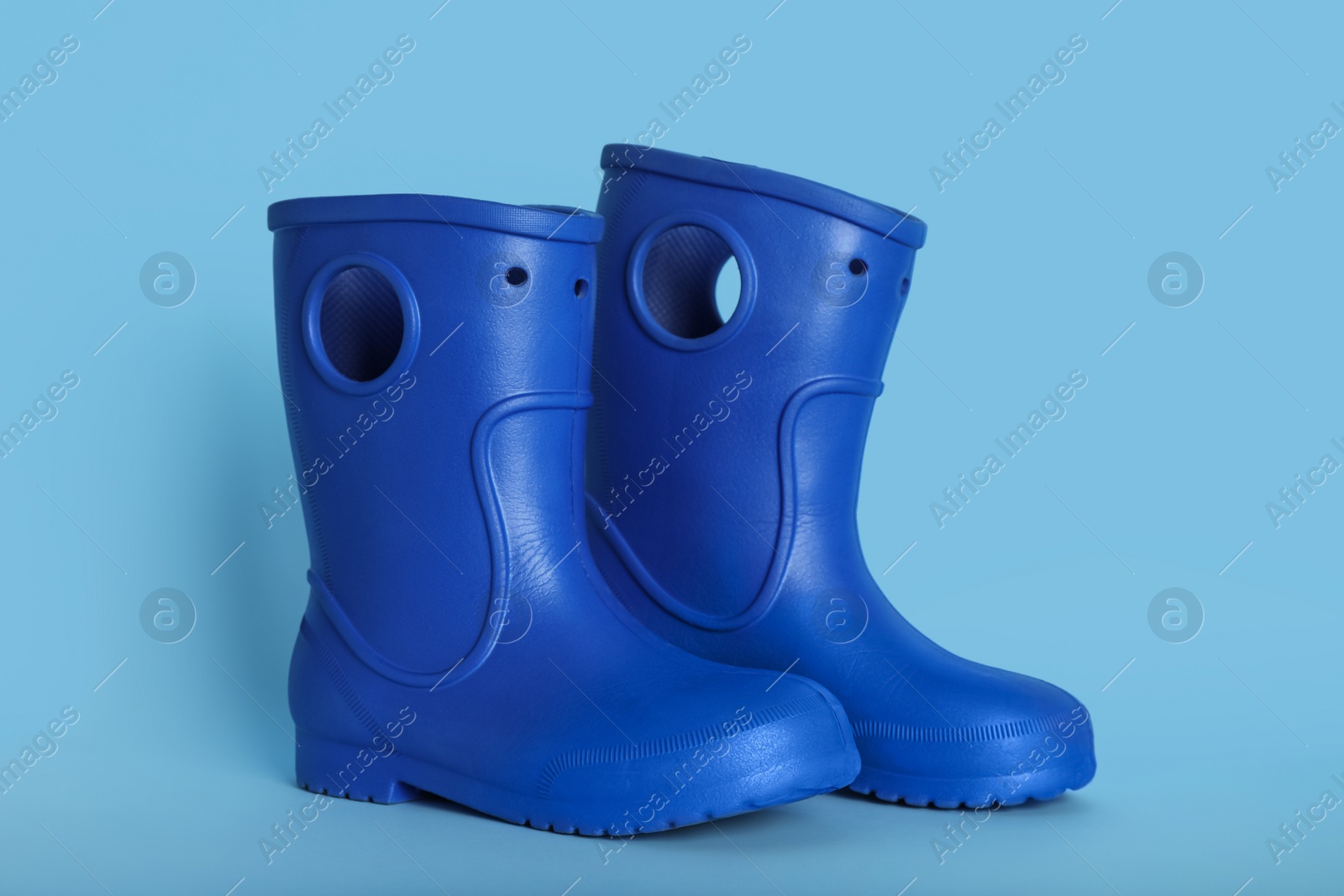 Photo of Pair of bright rubber boots on light blue background