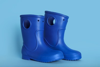 Photo of Pair of bright rubber boots on light blue background