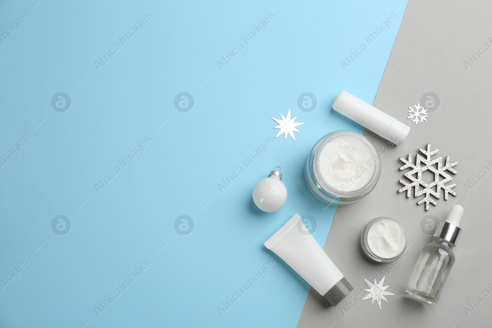 Photo of Flat lay composition with cosmetic products on light blue and grey background, space for text. Winter care