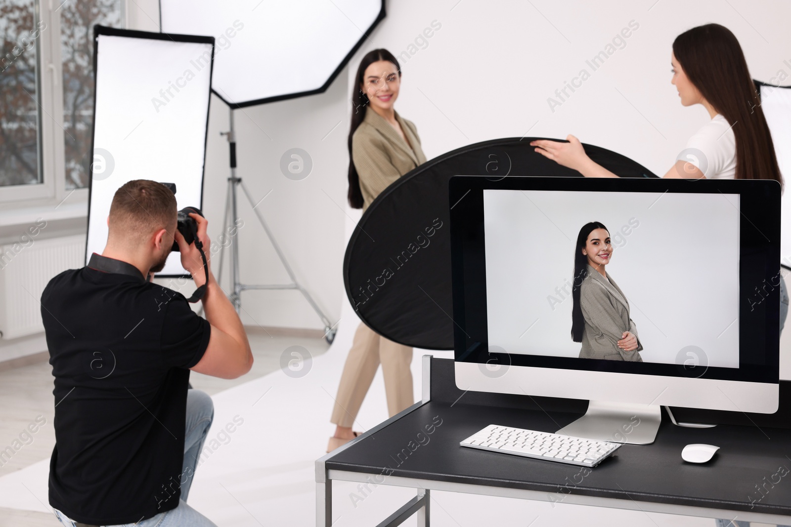 Photo of Professional photographer and assistant working with beautiful model in modern photo studio, selective focus