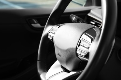 Photo of Black steering wheel inside of modern car, closeup. Space for text