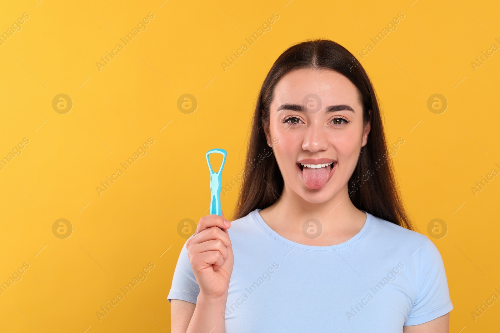 Photo of Happy woman with tongue cleaner on yellow background, space for text