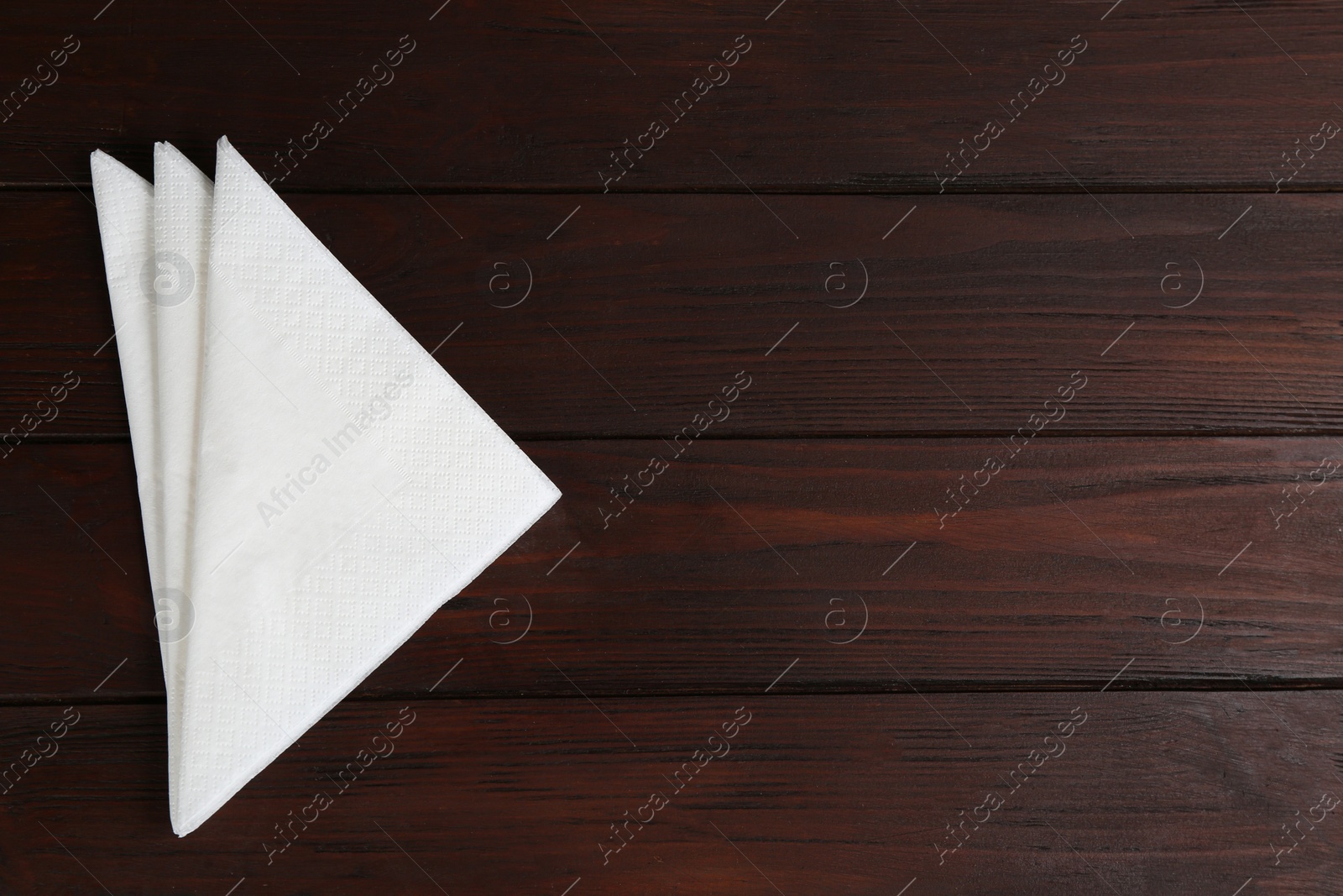 Photo of Clean napkins on wooden table, top view. Space for text