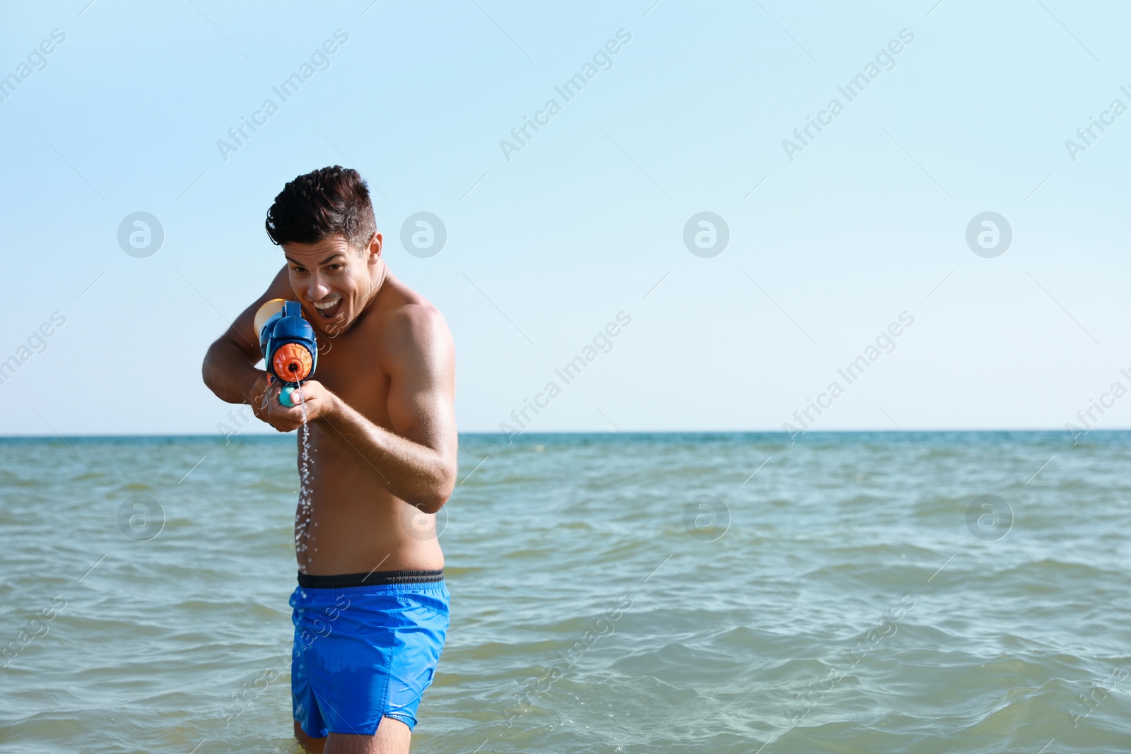 Photo of Man with water gun having fun in sea. Space for text