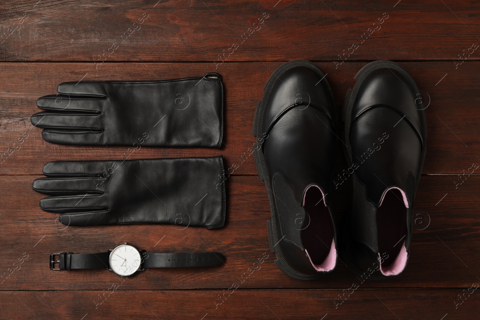 Photo of Stylish black leather gloves, pair of shoes and wristwatch on wooden table, flat lay