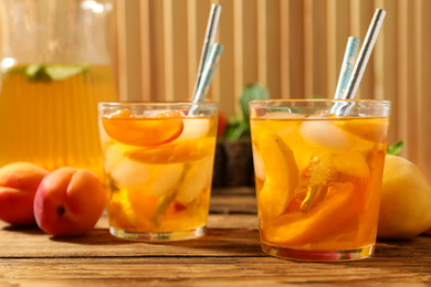 Photo of Delicious refreshing drink with apricot on wooden table, closeup