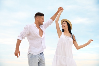 Photo of Happy young couple dancing outdoors in summer