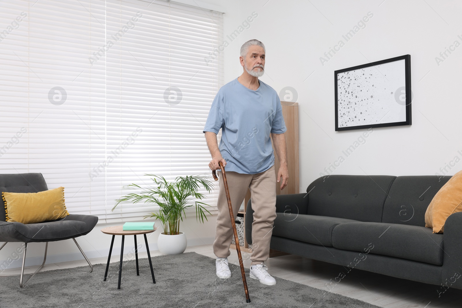 Photo of Senior man with walking cane at home