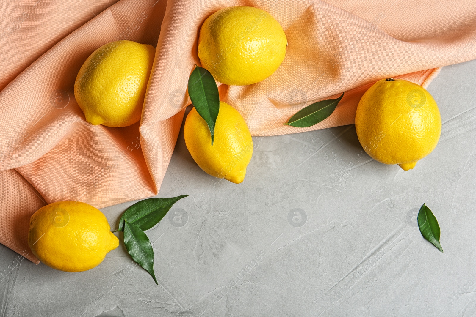 Photo of Composition with lemons, leaves and fabric on light background