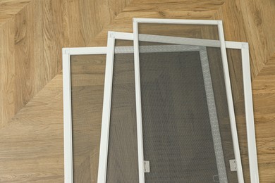 Photo of Set of window screens on wooden floor, flat lay