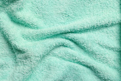 Photo of Soft crumpled light turquoise towel as background, top view