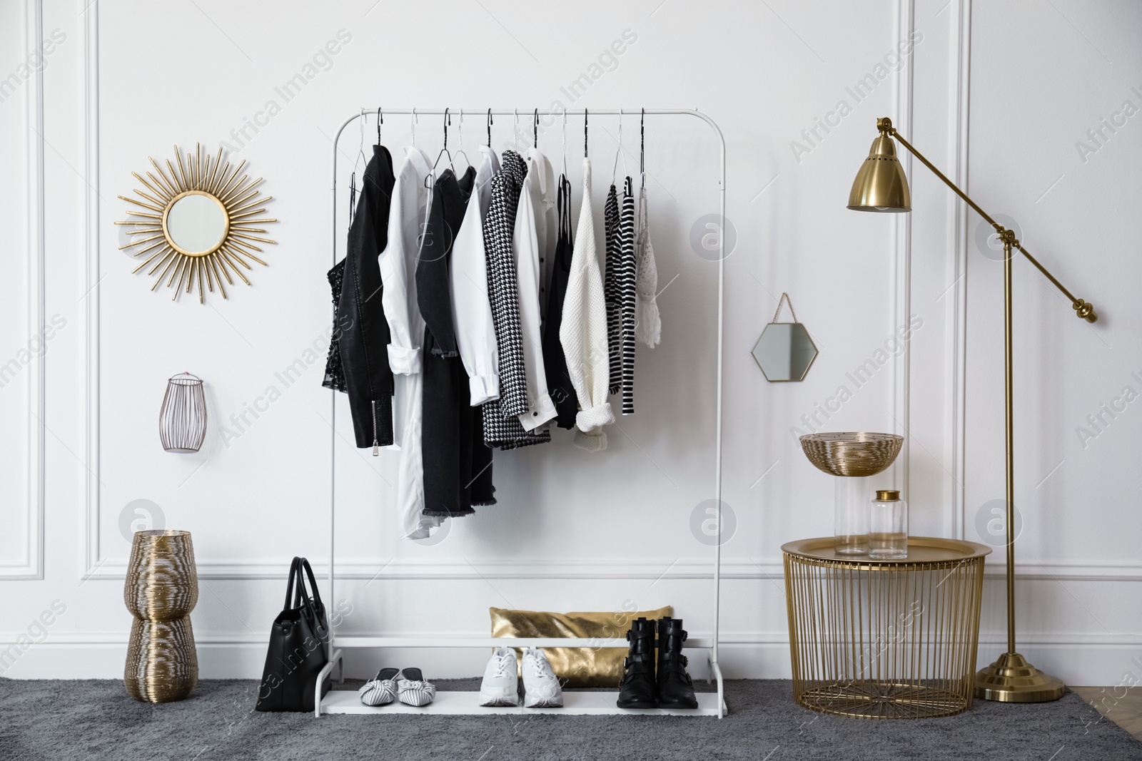 Photo of Rack with stylish clothes near white wall in dressing room