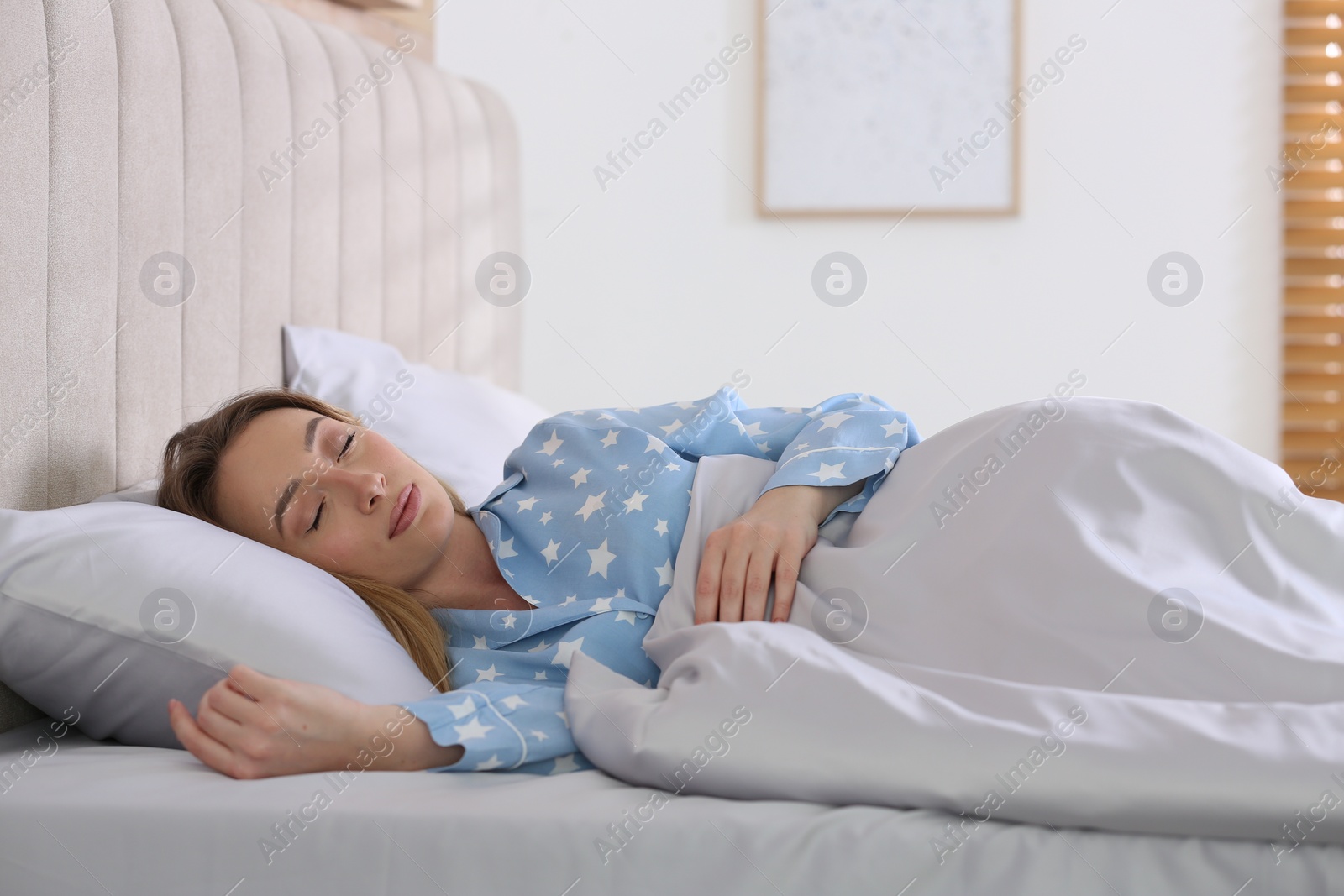 Photo of Young woman sleeping in comfortable bed with silky linens