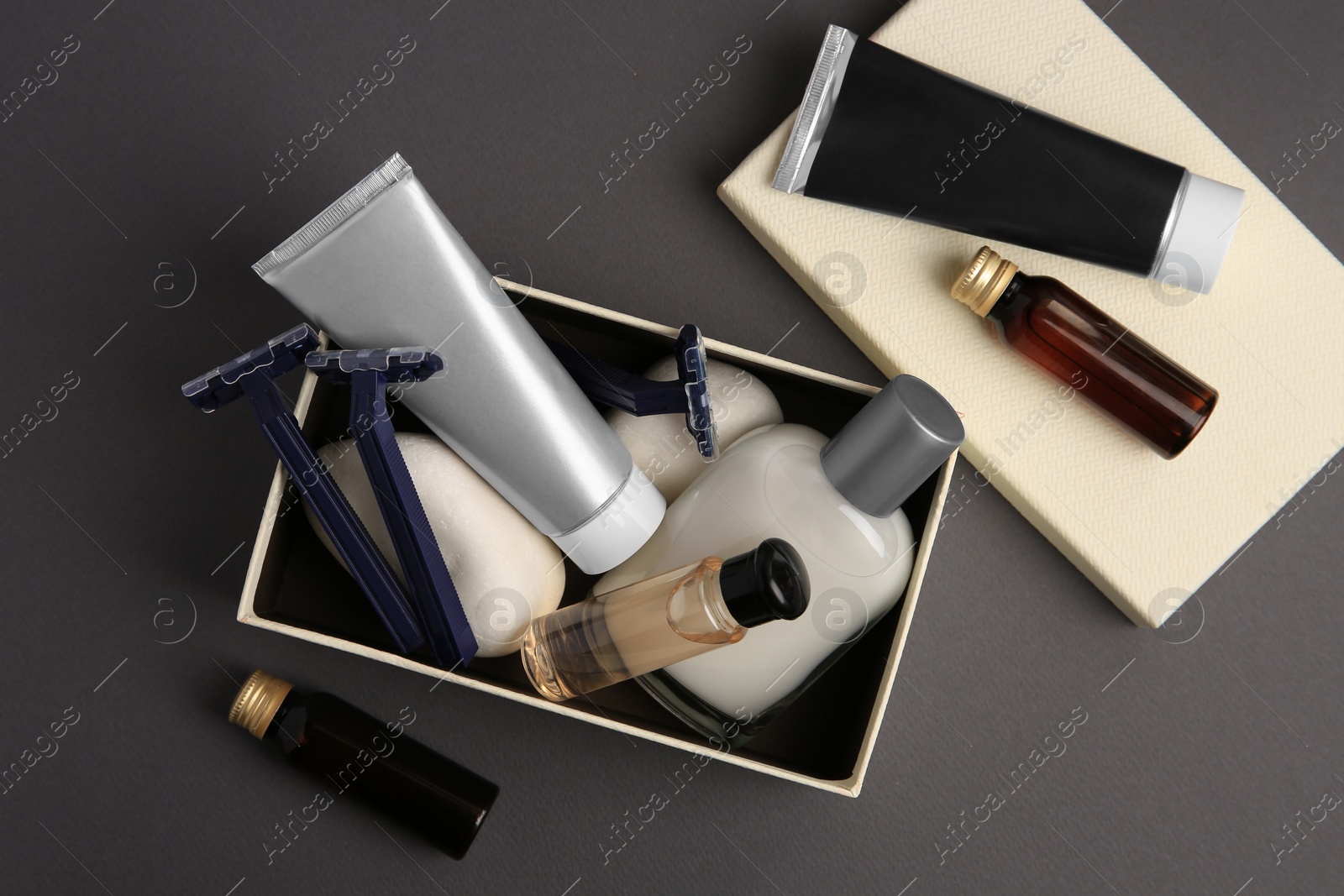 Photo of Different men's shaving accessories and box on dark grey background, flat lay