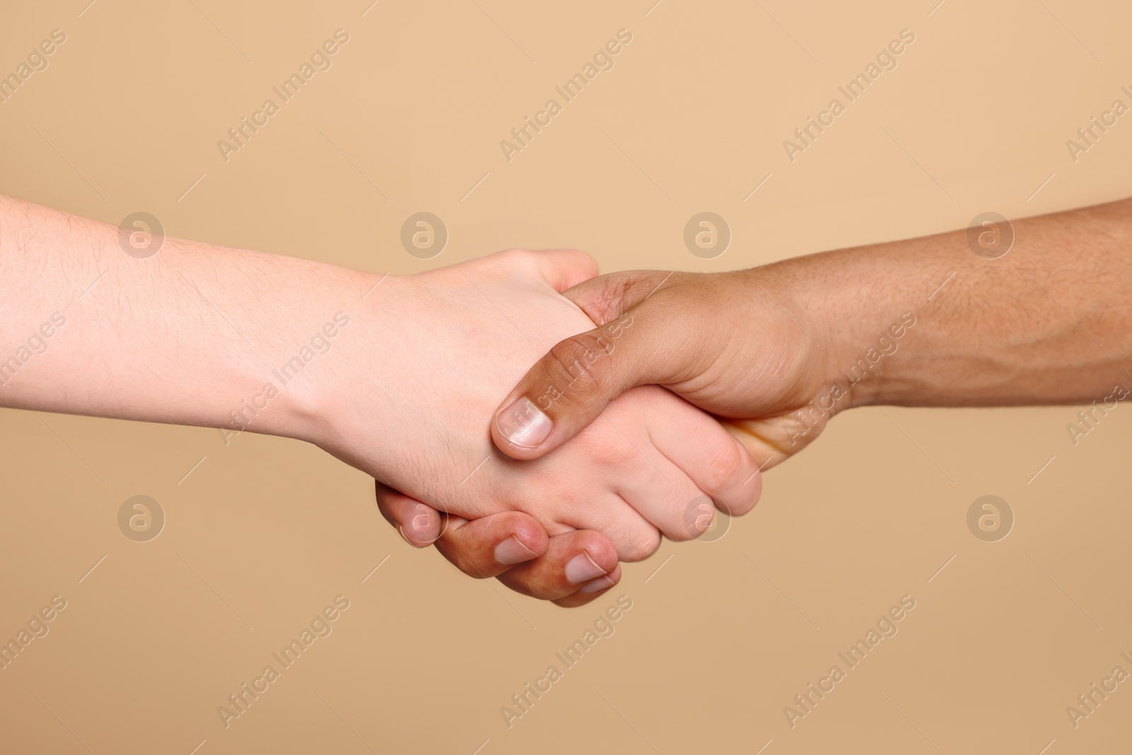 Photo of International relationships. People shaking hands on light brown background, closeup