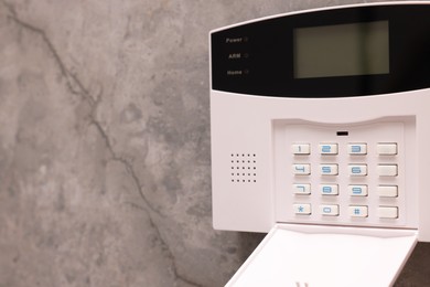Photo of Home security alarm system on grey wall, space for text