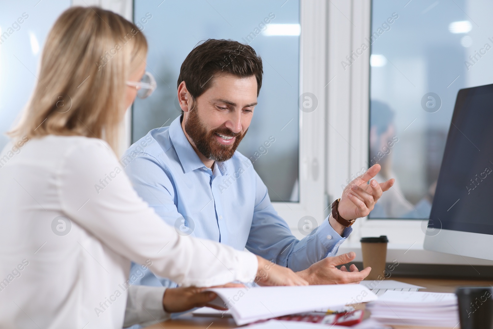 Photo of Happy businesspeople working with documents at table in office