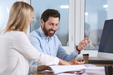 Photo of Happy businesspeople working with documents at table in office