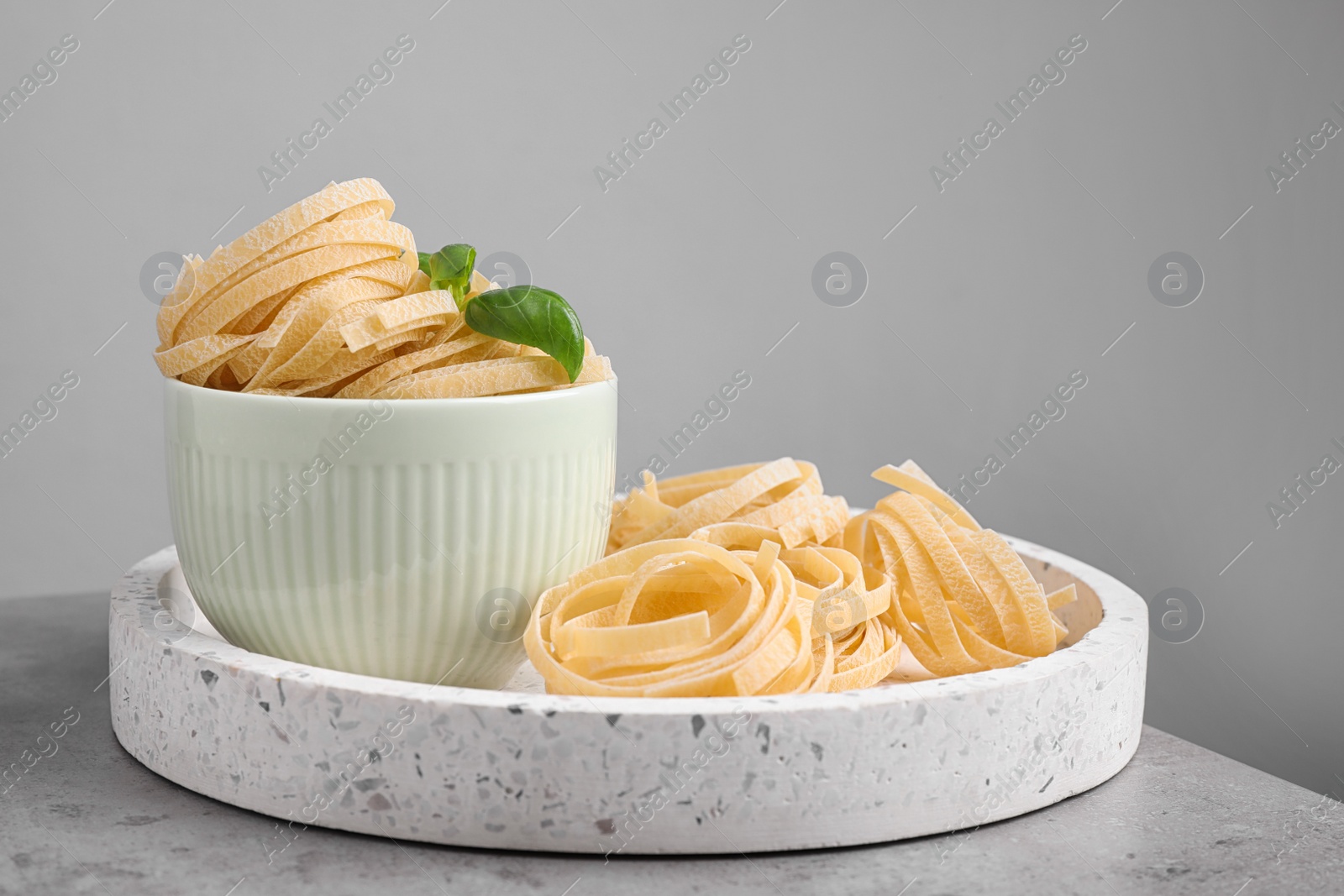 Photo of Uncooked tagliatelle pasta on table against grey background