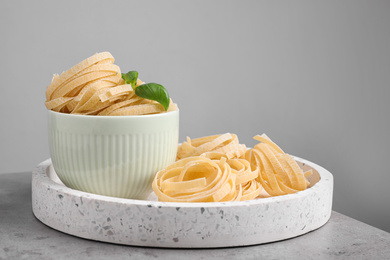 Uncooked tagliatelle pasta on table against grey background