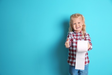 Photo of Cute little girl holding toilet paper roll on color background. Space for text