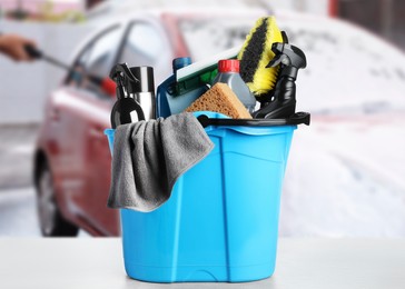 Bucket with cleaning supplies on table at car wash