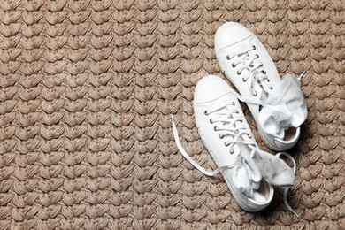 Photo of Sneakers with dirty socks on woven mat indoors, top view. Space for text