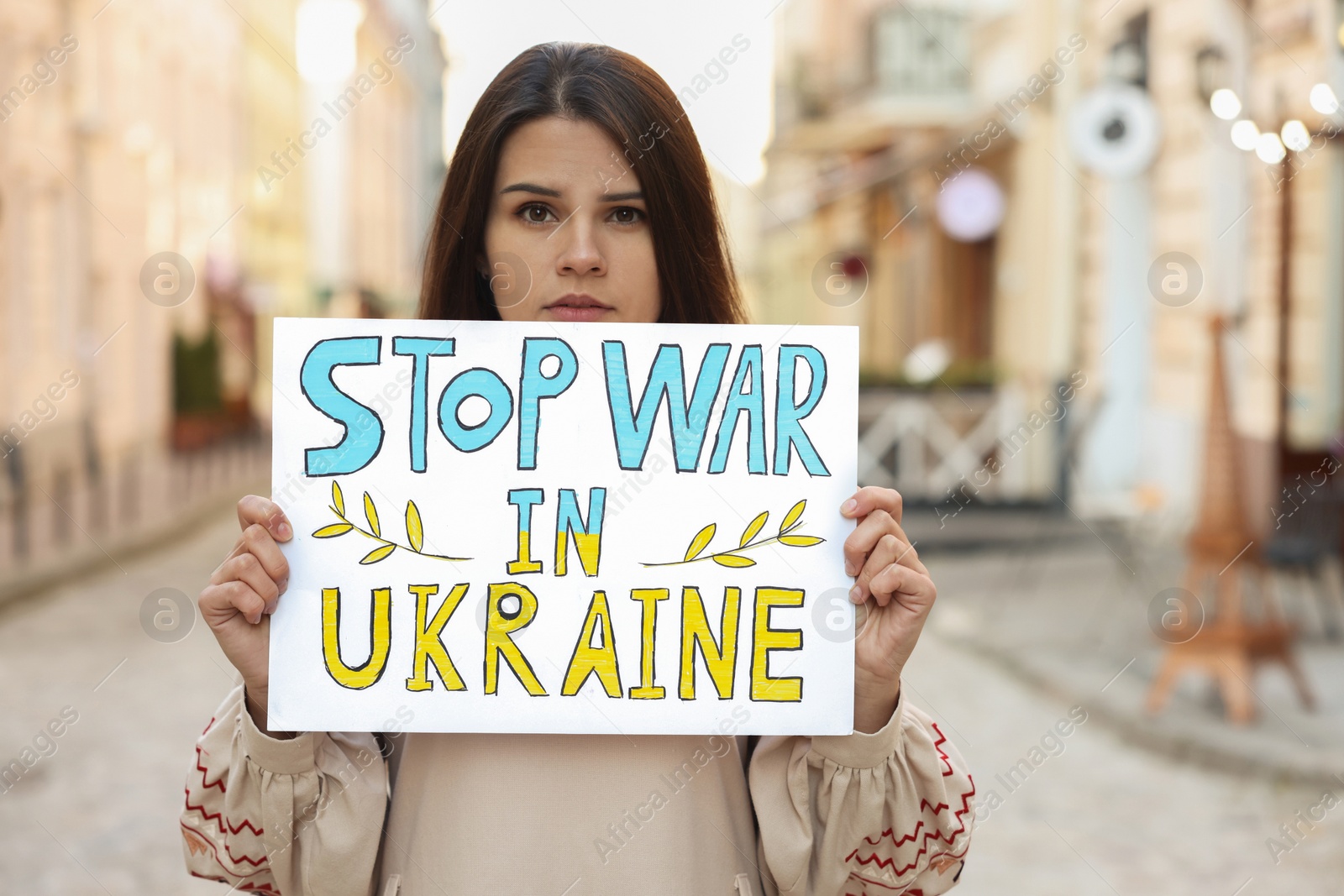 Photo of Sad woman holding poster Stop War in Ukraine on city street