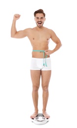 Photo of Fit man measuring his waist on bathroom scale against white background. Weight loss