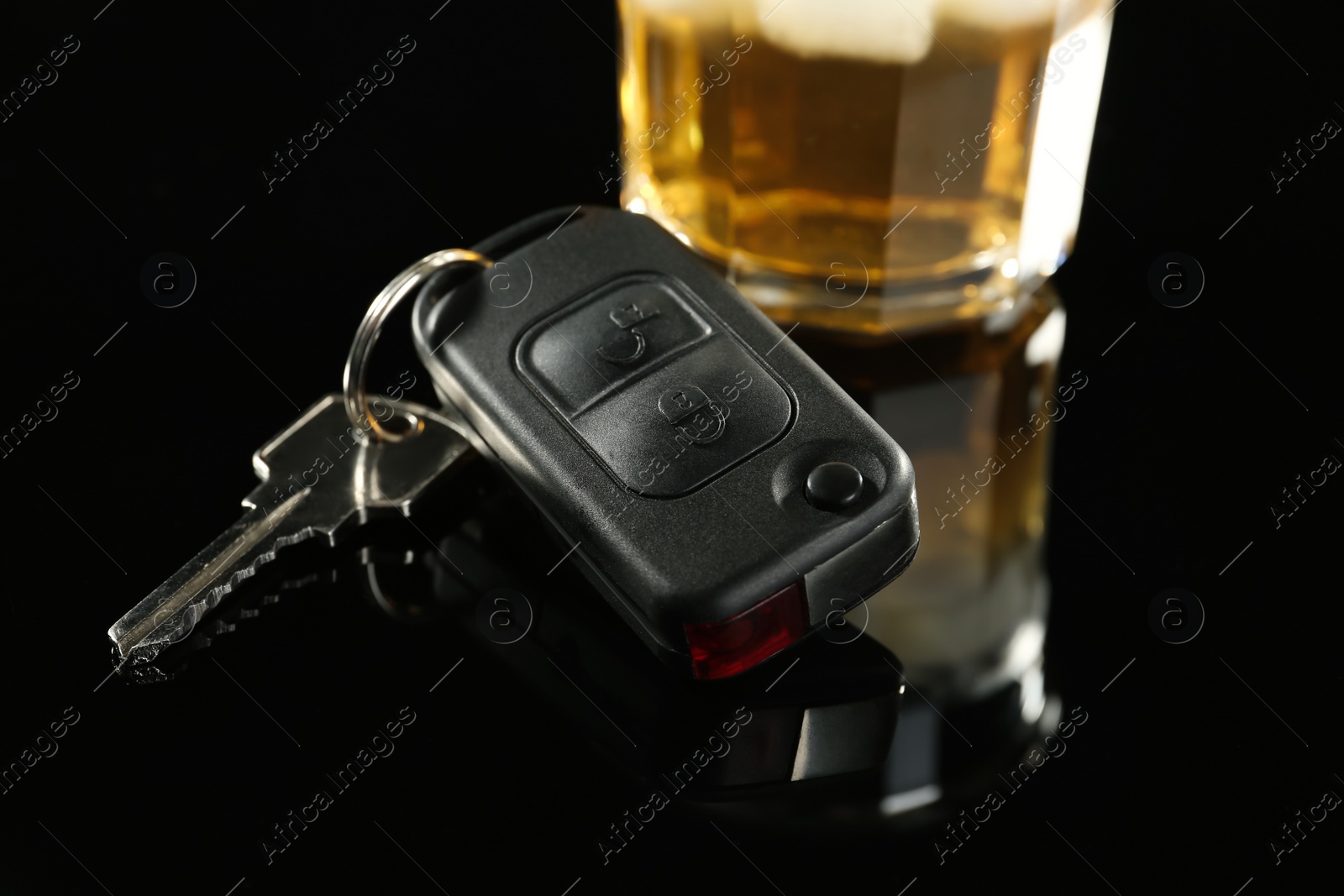 Photo of Car key near glass of alcohol on black table, closeup. Dangerous drinking and driving