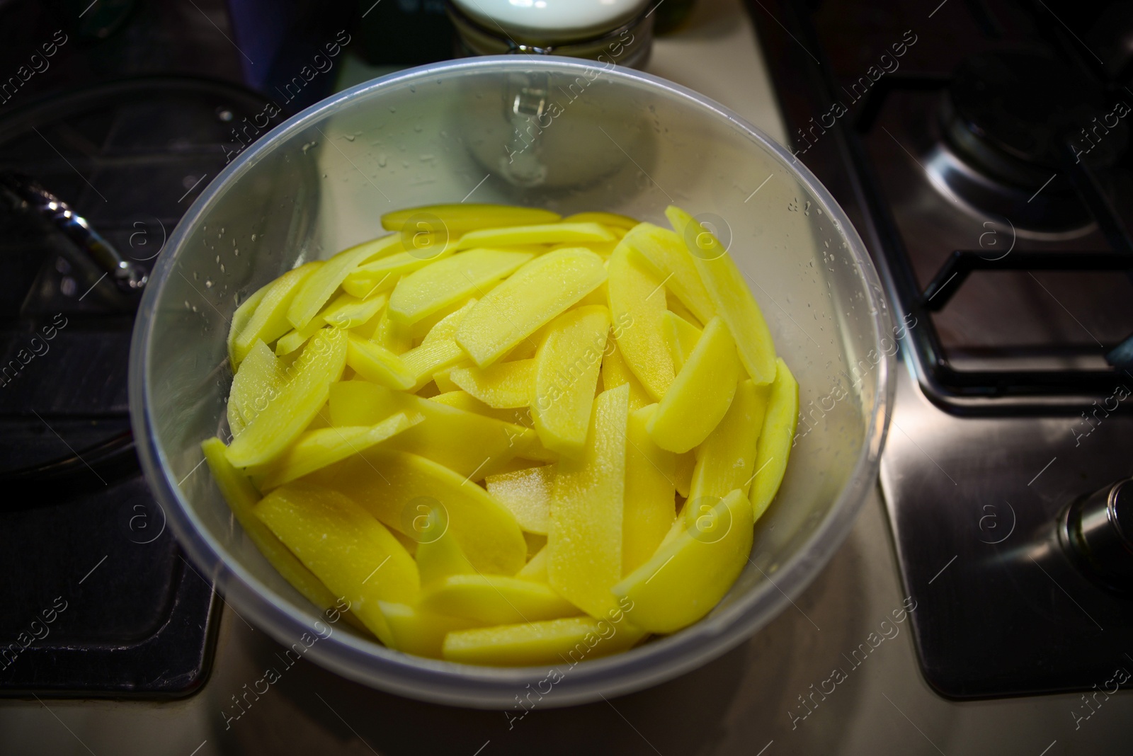 Photo of Bowl with cut raw potatoes on countertop