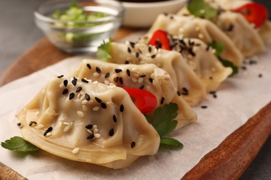 Photo of Delicious gyoza (asian dumplings) with sesame seeds on wooden board, closeup