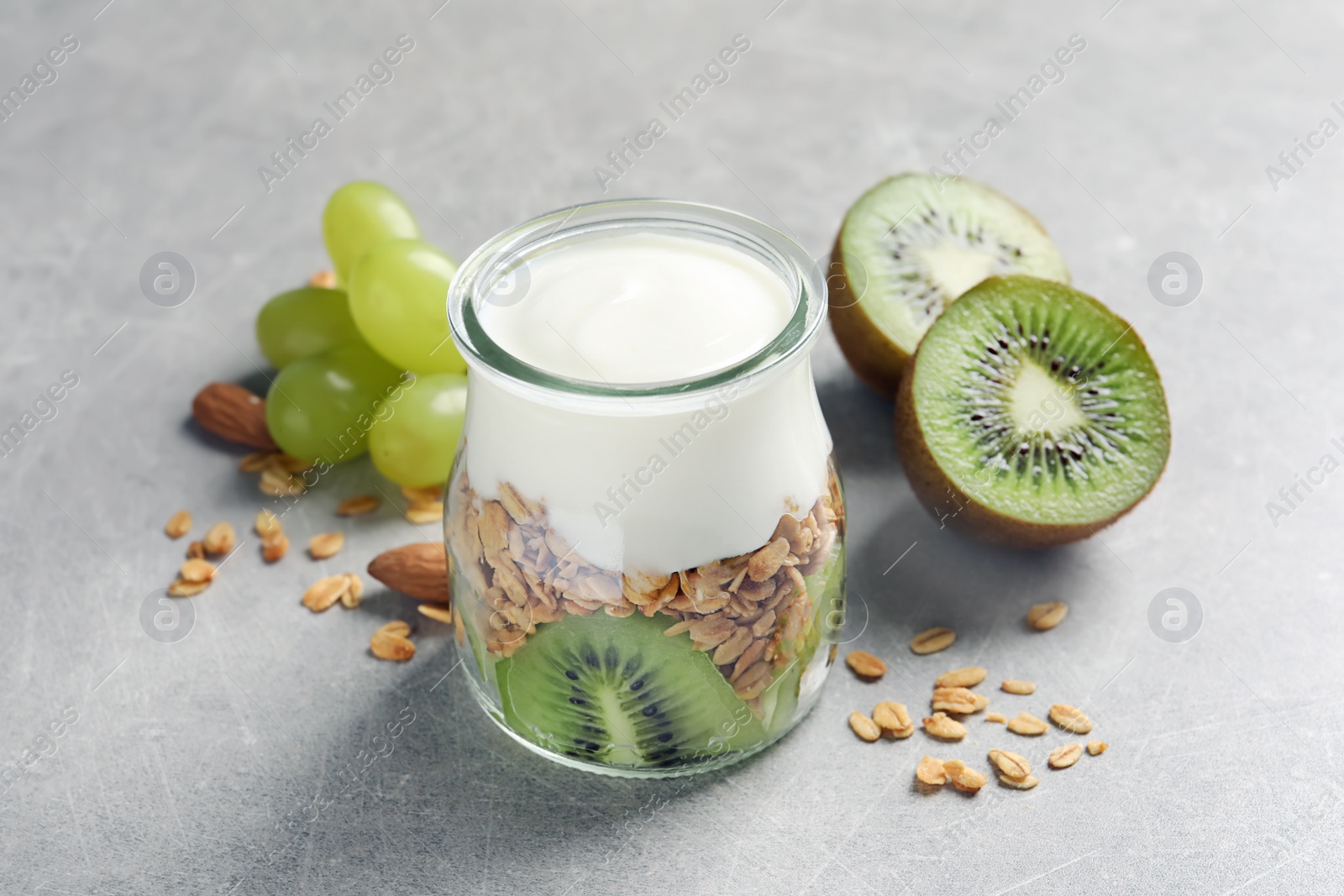 Photo of Jar with yogurt, granola and fruits on table