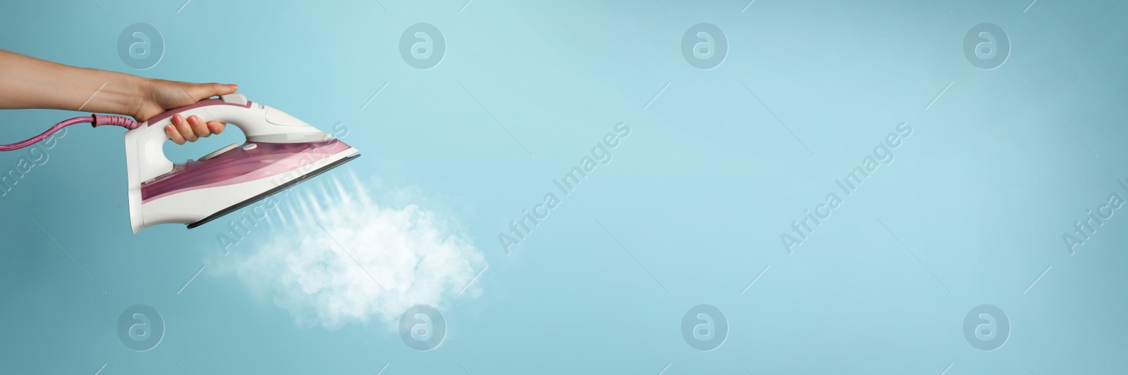 Image of Woman with iron on light blue background, closeup. Banner design with space for text