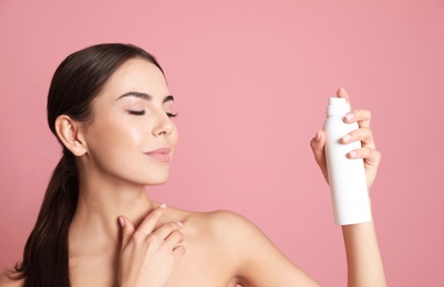 Photo of Young woman with bottle of thermal water on color background. Cosmetic product