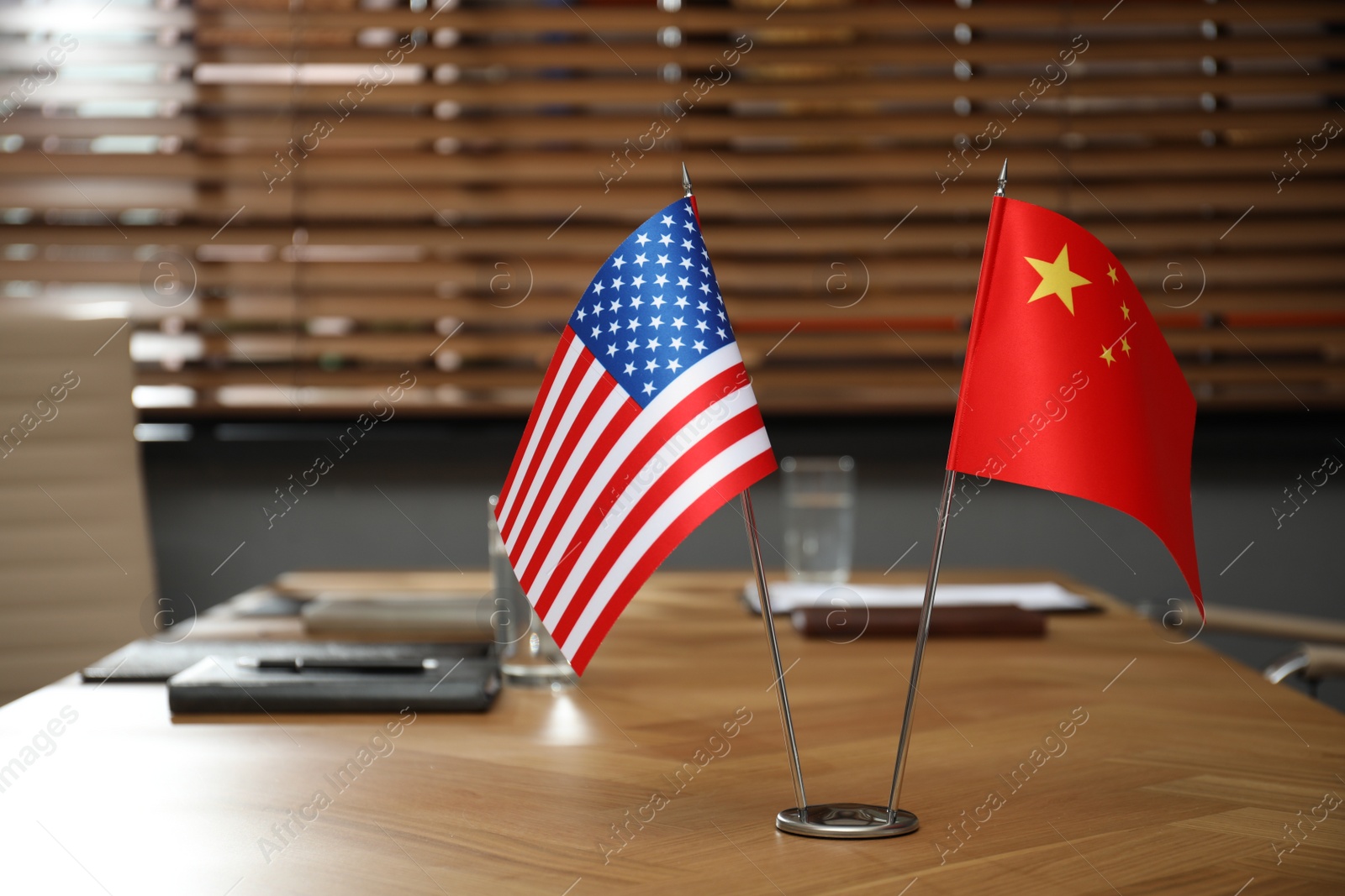 Photo of USA and China flags on wooden table in office. International relations