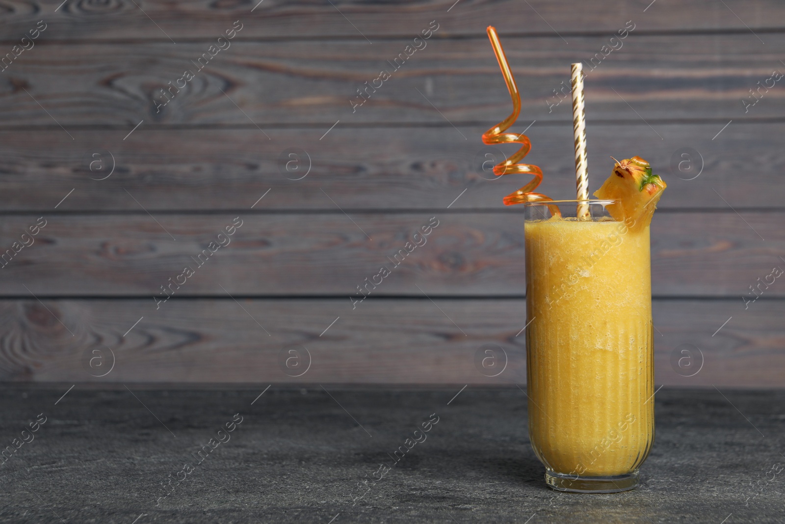 Photo of Tasty pineapple smoothie on black textured table. Space for text