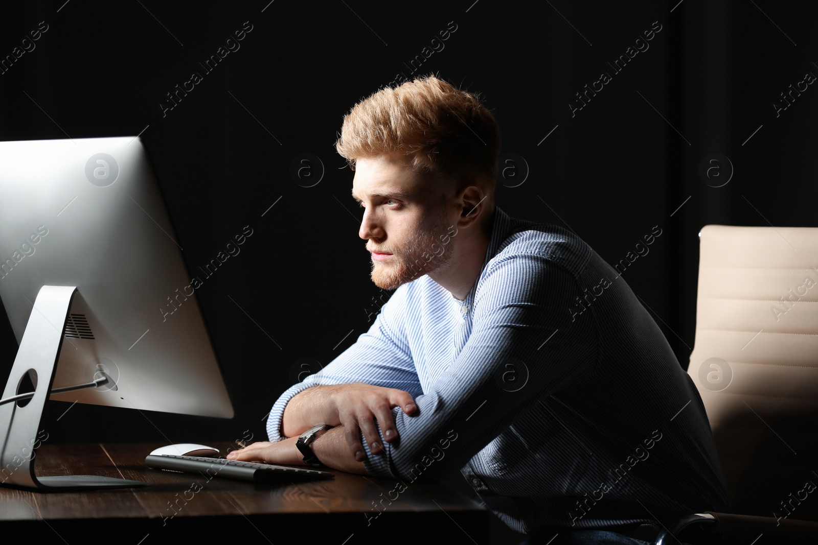 Photo of Tired young man working in office alone at night