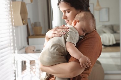 Happy young mother with her sleeping baby at home