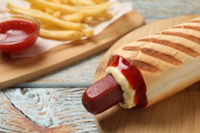 Photo of Delicious french hot dog, fries and dip sauce on rustic wooden table, closeup